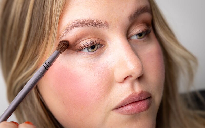 Lidschatten wird mit einem Pinsel auf die Augen aufgetragen